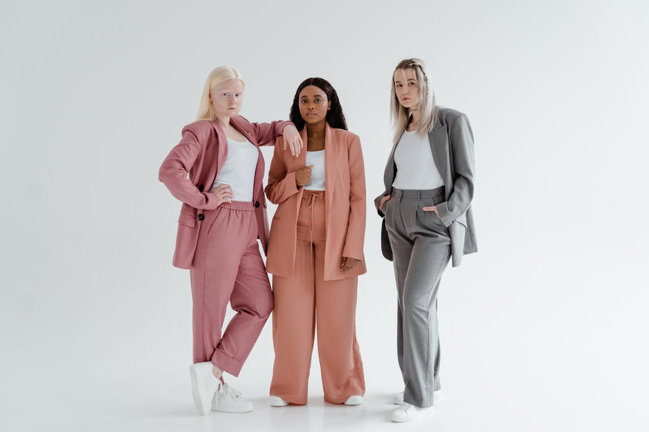 services-01 Three diverse women in stylish suits standing confidently in a studio.