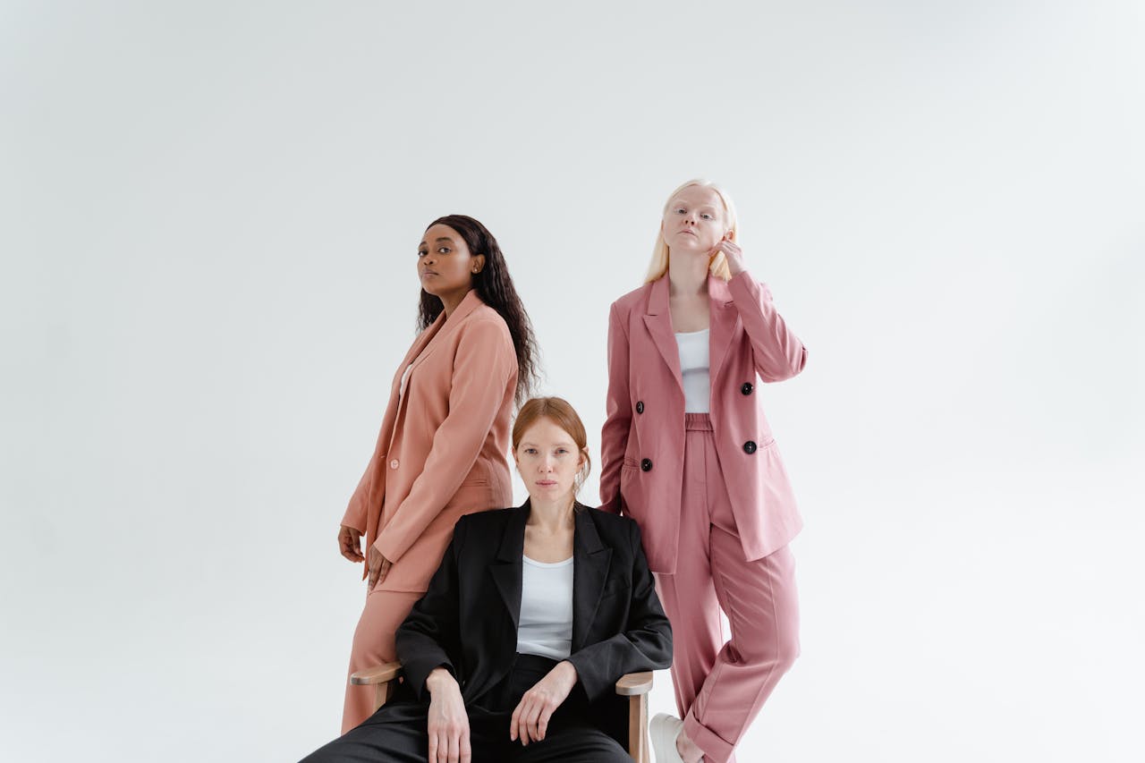 hero-img-01 Three diverse businesswomen in stylish suits on a studio white background, exuding confidence.